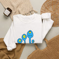 White Darlene Schnerd Crewneck Sweatshirt, styled on a table with the character print visible